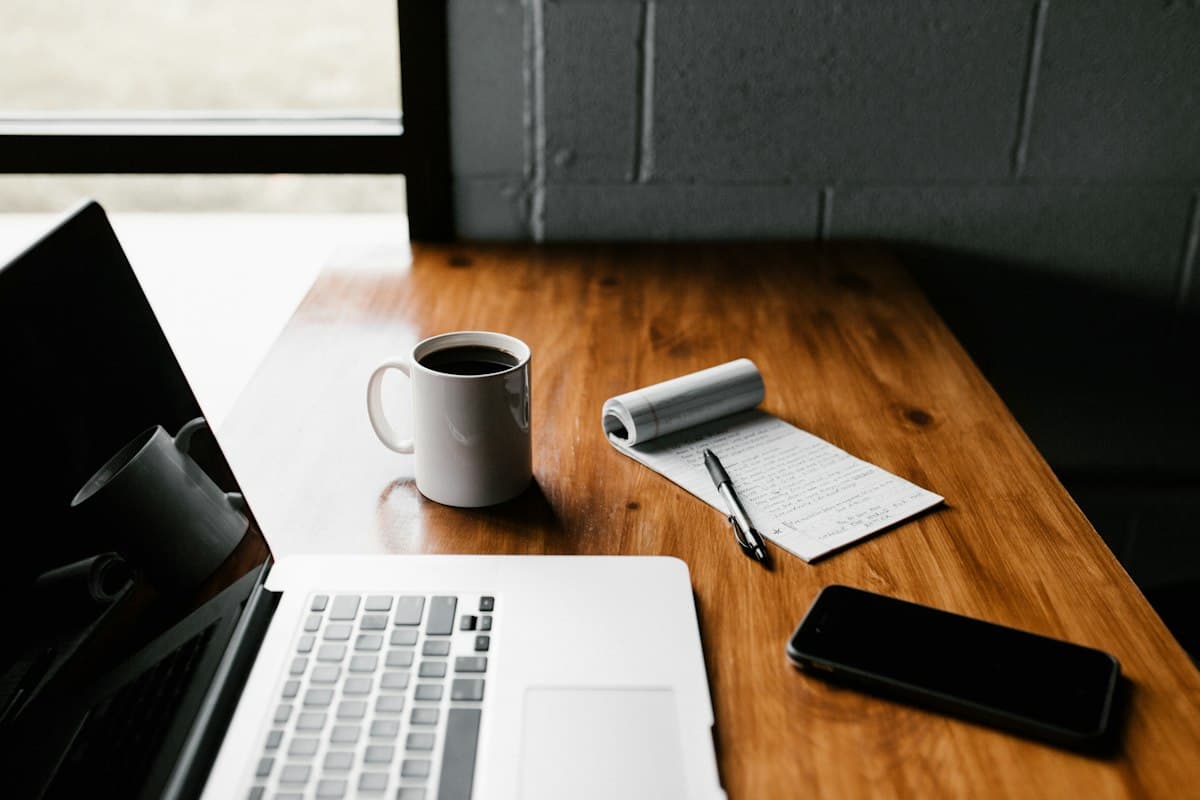 Ordinateur portable, carnet et café sur un bureau en bois